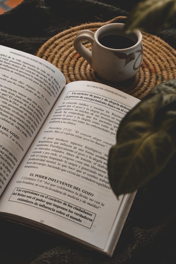 Libro abierto con taza de café sobre mesa — libros espirituales recomendados